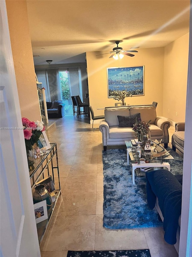 living room featuring ceiling fan, tile patterned floors, and a textured ceiling