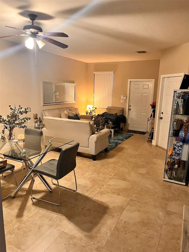 living room featuring ceiling fan and a textured ceiling