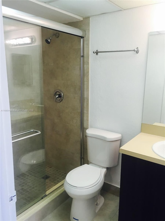 bathroom with tile patterned floors, an enclosed shower, vanity, and toilet