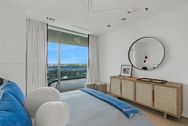 bedroom with a water view, expansive windows, access to outside, and multiple windows