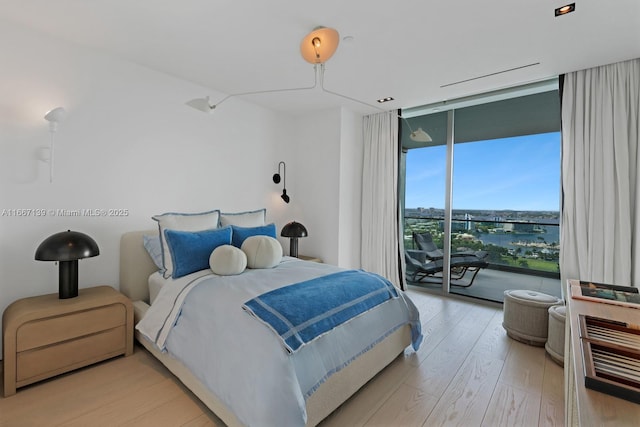 bedroom with access to exterior, expansive windows, and light hardwood / wood-style floors