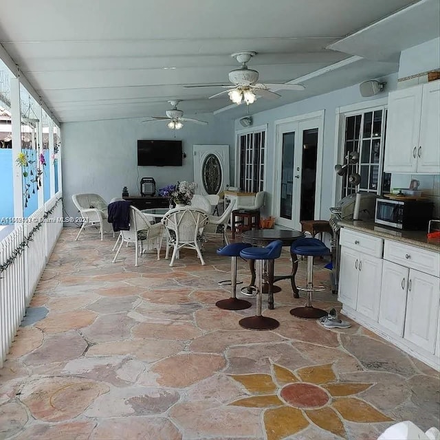 interior space with ceiling fan, french doors, vaulted ceiling, and white cabinetry