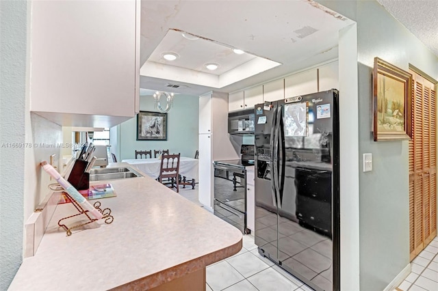 kitchen featuring light tile patterned flooring, sink, white cabinetry, black appliances, and a raised ceiling