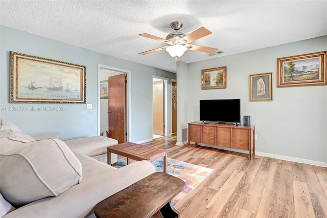 living room featuring a textured ceiling, ceiling fan, and light hardwood / wood-style flooring