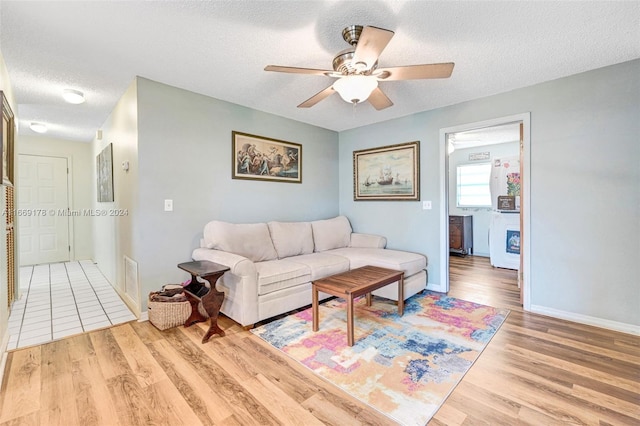 living room with light hardwood / wood-style flooring, ceiling fan, and a textured ceiling