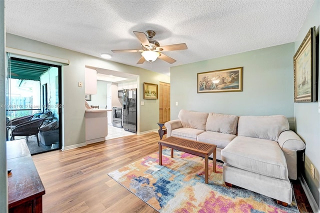 living room featuring a textured ceiling, light hardwood / wood-style floors, and ceiling fan