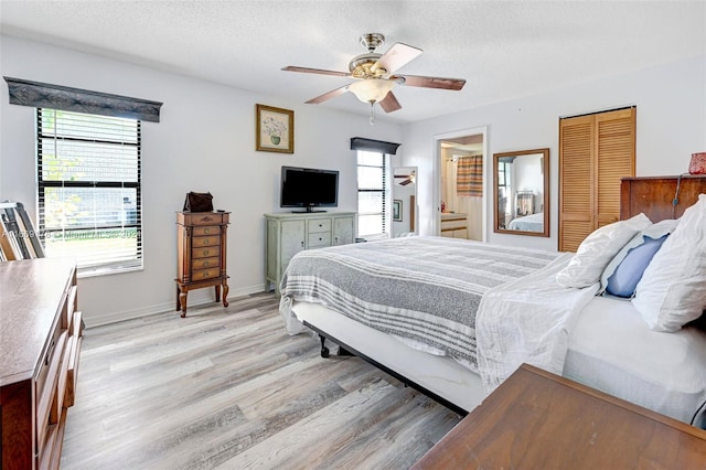 bedroom featuring a closet, light wood-type flooring, ceiling fan, and a textured ceiling