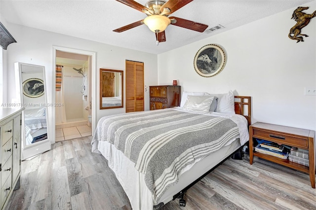 bedroom with ceiling fan, light hardwood / wood-style floors, a textured ceiling, a closet, and ensuite bathroom