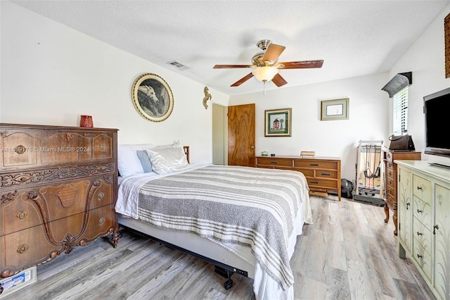 bedroom featuring a textured ceiling, ceiling fan, and light hardwood / wood-style flooring