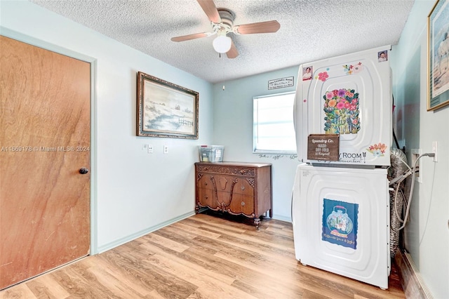 interior space with stacked washer / dryer, a textured ceiling, ceiling fan, and light hardwood / wood-style flooring