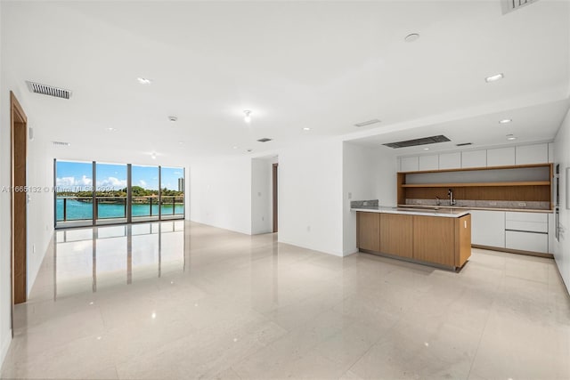 kitchen featuring white cabinets, a water view, and light tile patterned floors