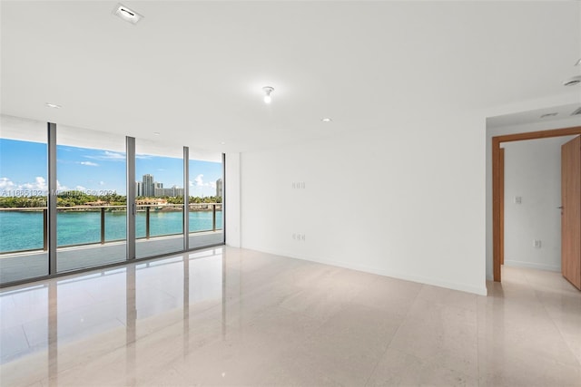 unfurnished room featuring expansive windows and a water view