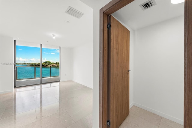 hall with floor to ceiling windows and a water view