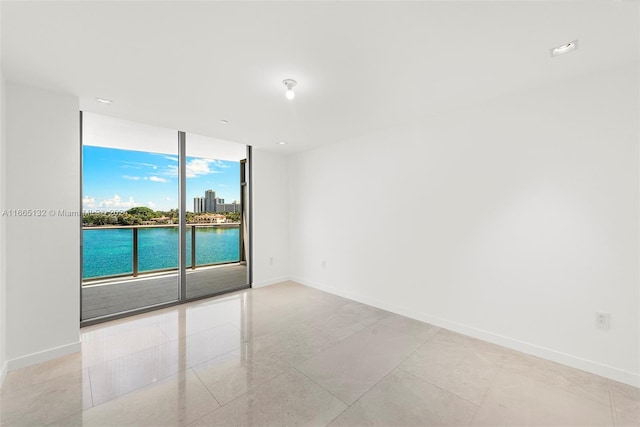 unfurnished room with a water view and a wall of windows