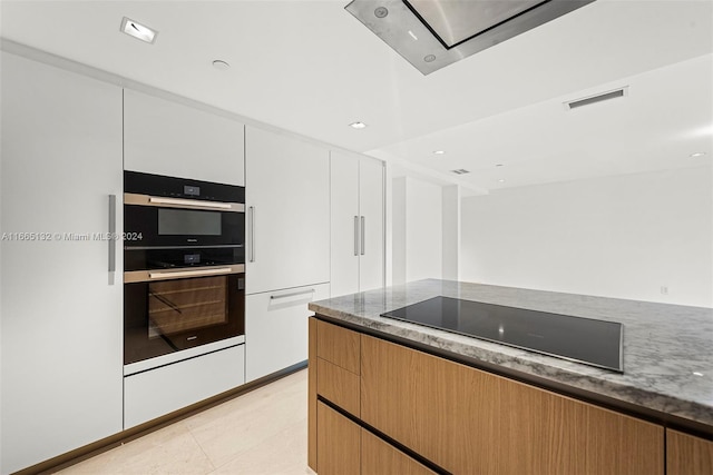 kitchen featuring dark stone counters, white cabinets, and black appliances