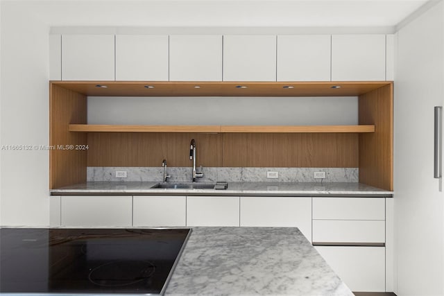 kitchen with white cabinetry, sink, and black cooktop