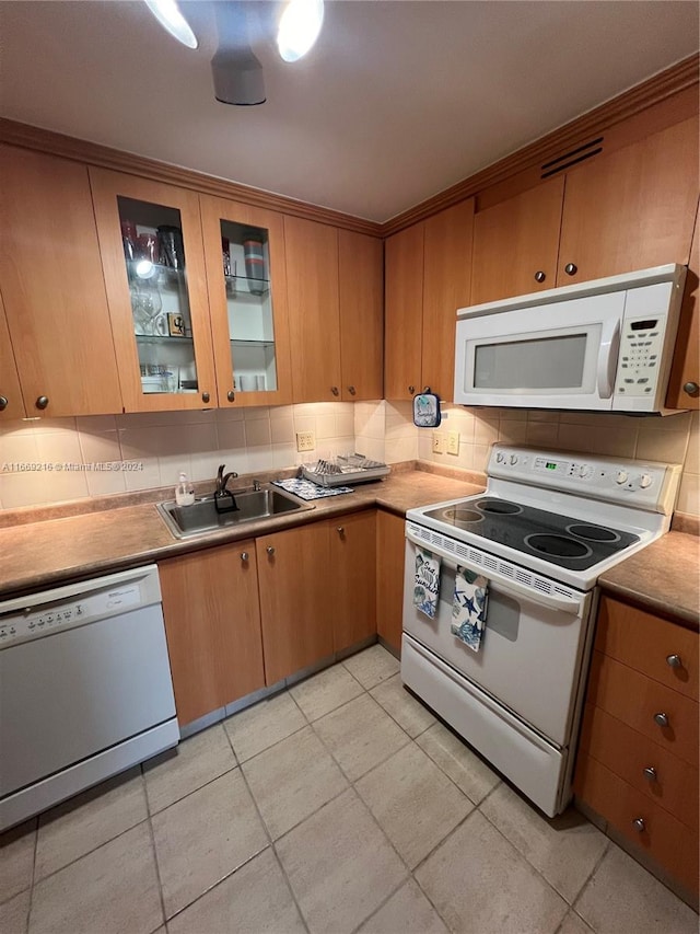 kitchen with backsplash, white appliances, and sink