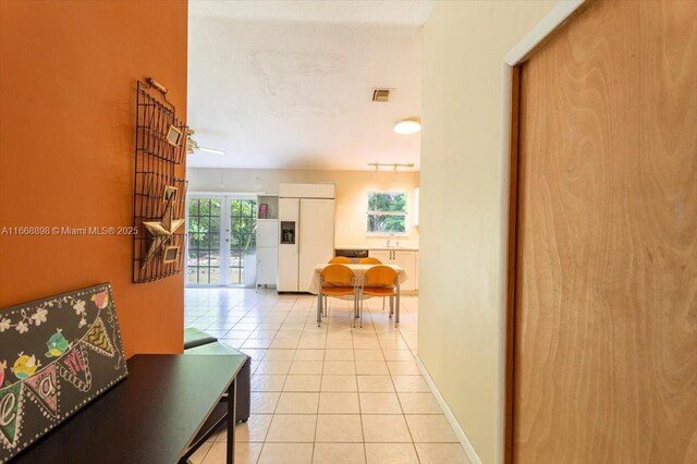 corridor with french doors, light tile patterned floors, visible vents, a sink, and baseboards