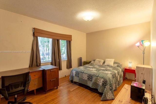 bedroom with a textured ceiling and light wood finished floors