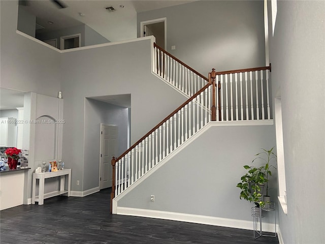 staircase featuring a towering ceiling and hardwood / wood-style flooring