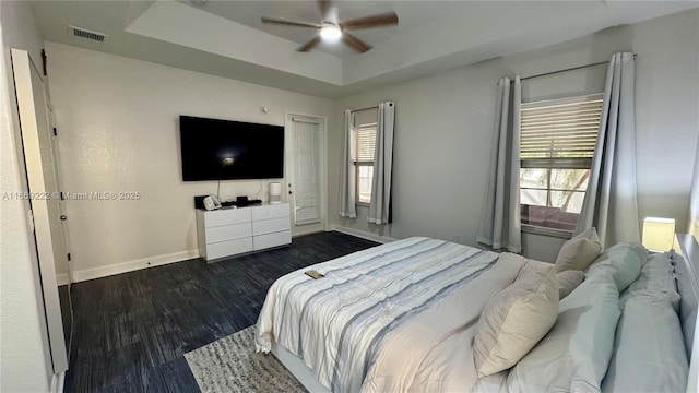 bedroom featuring dark hardwood / wood-style flooring, a raised ceiling, and ceiling fan