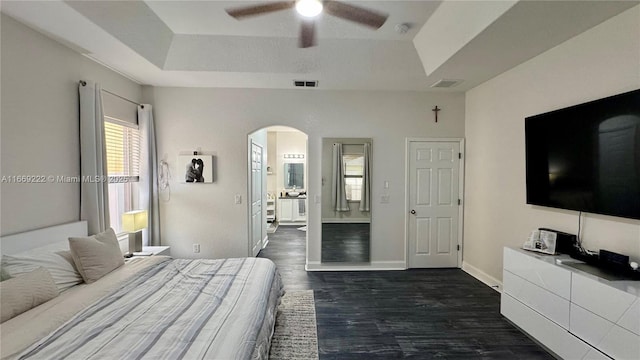 bedroom with a raised ceiling, ensuite bathroom, ceiling fan, and dark hardwood / wood-style floors