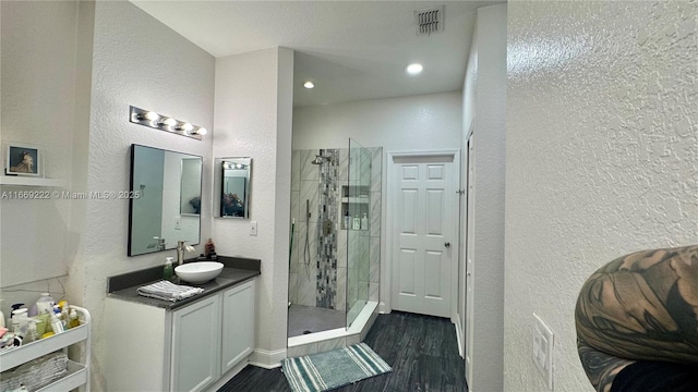 bathroom featuring hardwood / wood-style floors, vanity, and tiled shower