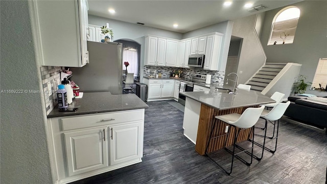 kitchen featuring white cabinetry, sink, stainless steel appliances, dark hardwood / wood-style floors, and kitchen peninsula