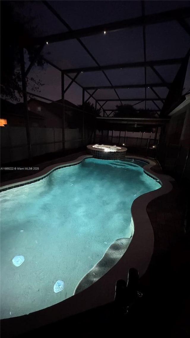 view of pool with a lanai and an in ground hot tub