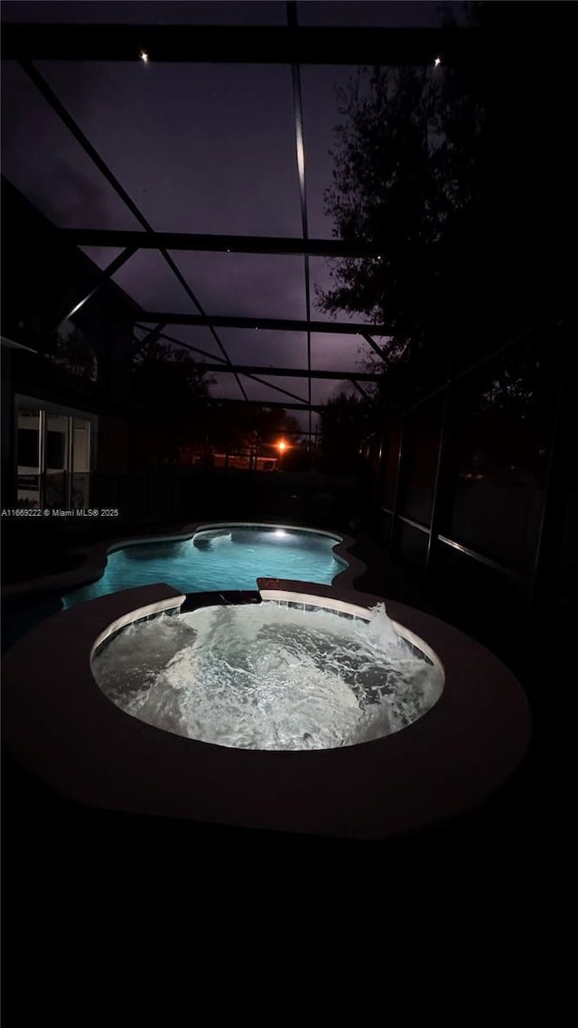 view of swimming pool with an in ground hot tub and a lanai