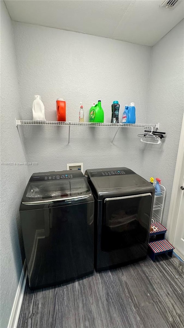 laundry room with washer and dryer and dark wood-type flooring