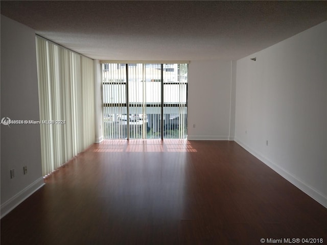 empty room featuring a wall of windows, a textured ceiling, and hardwood / wood-style flooring