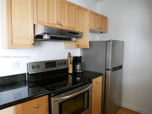 kitchen with ventilation hood, appliances with stainless steel finishes, and dark stone counters