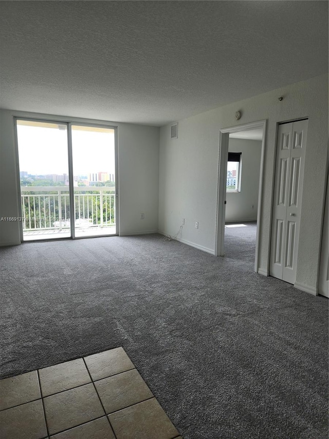 carpeted empty room with a textured ceiling