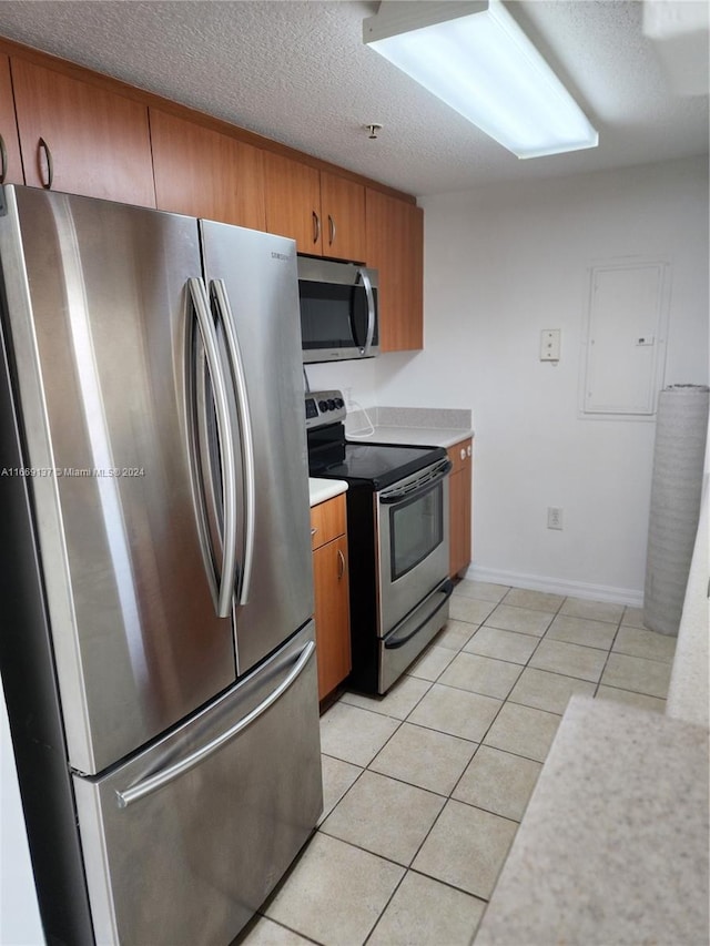 kitchen featuring stainless steel appliances, a textured ceiling, and light tile patterned floors