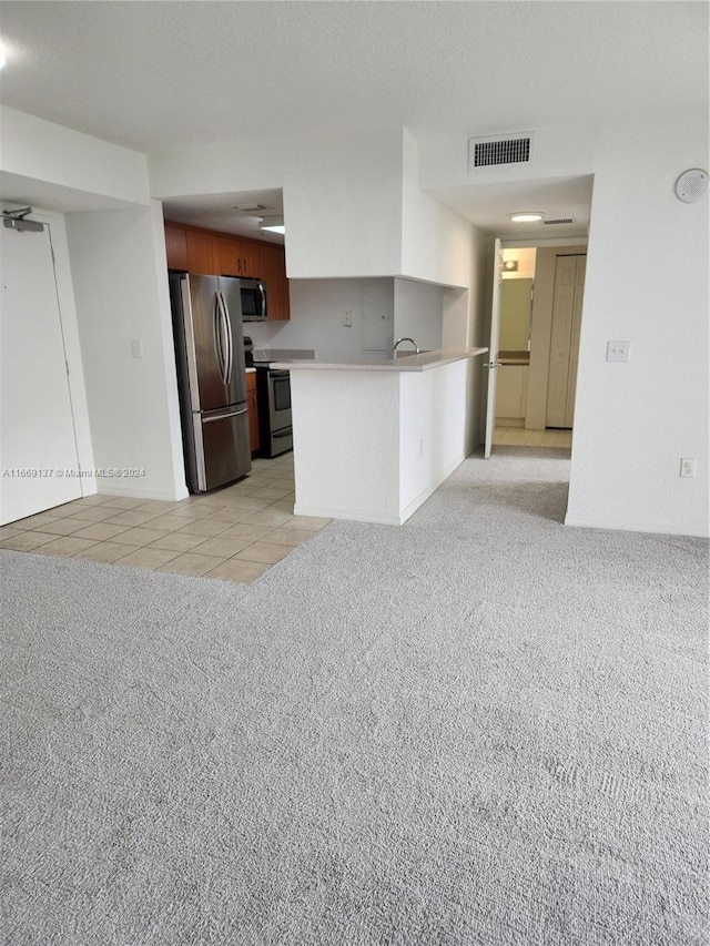 kitchen featuring light carpet, kitchen peninsula, ceiling fan, and appliances with stainless steel finishes