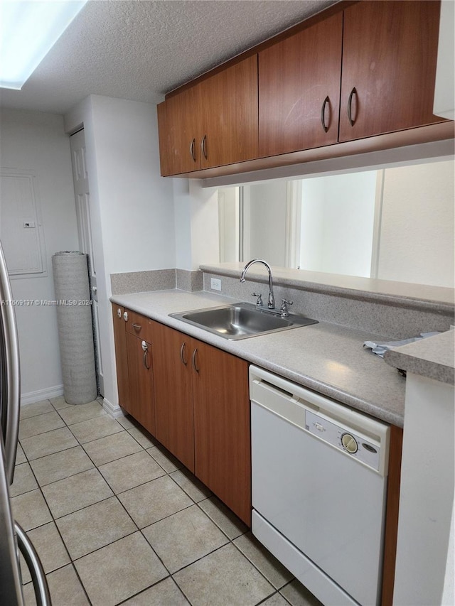 kitchen with white dishwasher, a textured ceiling, light tile patterned floors, and sink