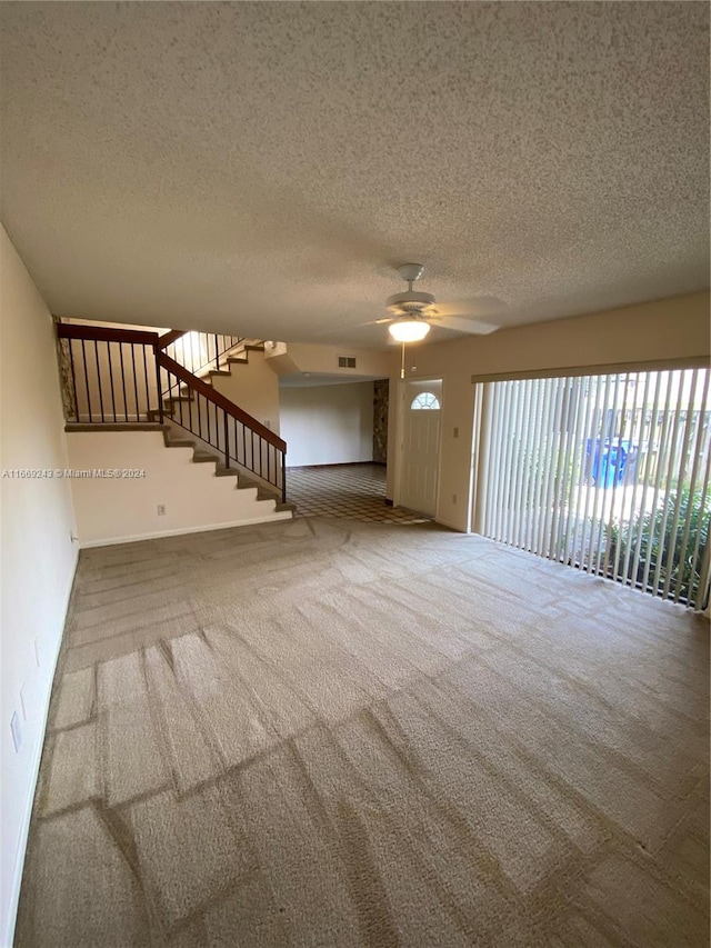 unfurnished living room with carpet, ceiling fan, and a textured ceiling