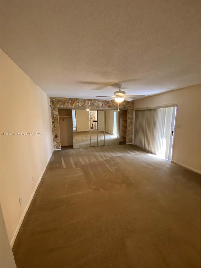 unfurnished living room with ceiling fan, carpet flooring, and a textured ceiling