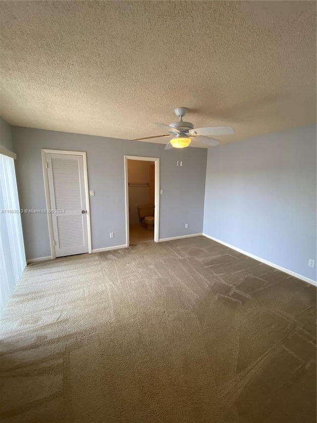 empty room featuring ceiling fan, carpet flooring, and a textured ceiling