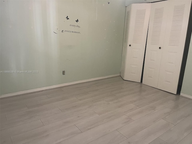 unfurnished bedroom with a closet, light wood-type flooring, and baseboards