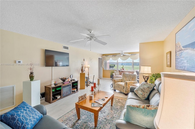 living room featuring ceiling fan and a textured ceiling