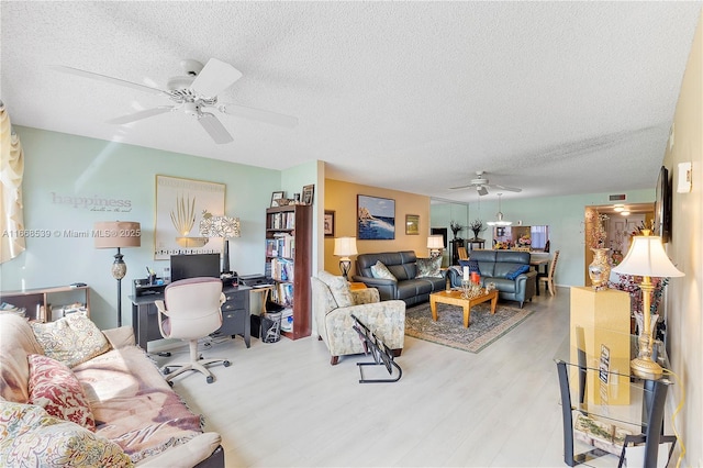 living room with ceiling fan, light hardwood / wood-style flooring, and a textured ceiling