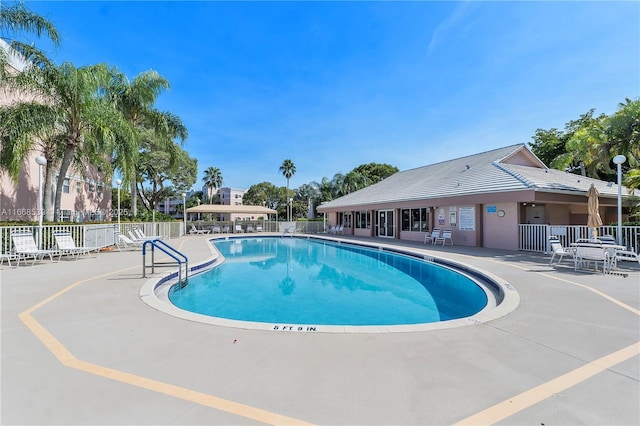 pool with a patio area and fence