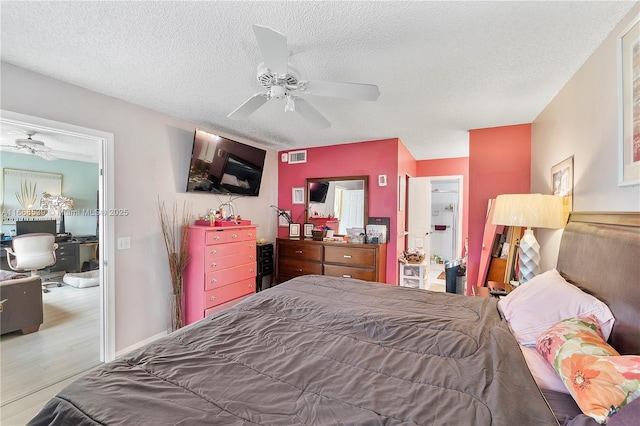 bedroom with hardwood / wood-style flooring, ceiling fan, and a textured ceiling