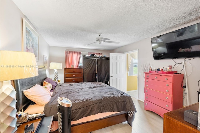 bedroom with light wood-type flooring, a textured ceiling, and ceiling fan