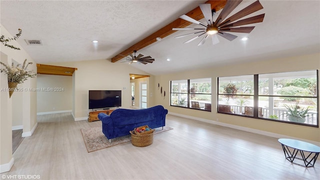 living room with a textured ceiling, lofted ceiling with beams, light hardwood / wood-style flooring, and ceiling fan