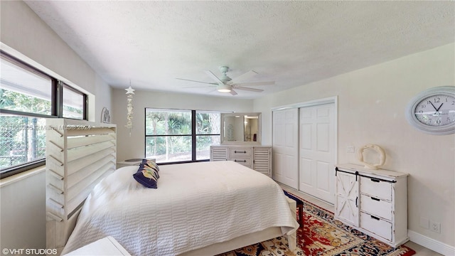 bedroom featuring a textured ceiling, ceiling fan, multiple windows, and a closet