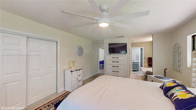 bedroom with ceiling fan, ensuite bathroom, a textured ceiling, and a closet