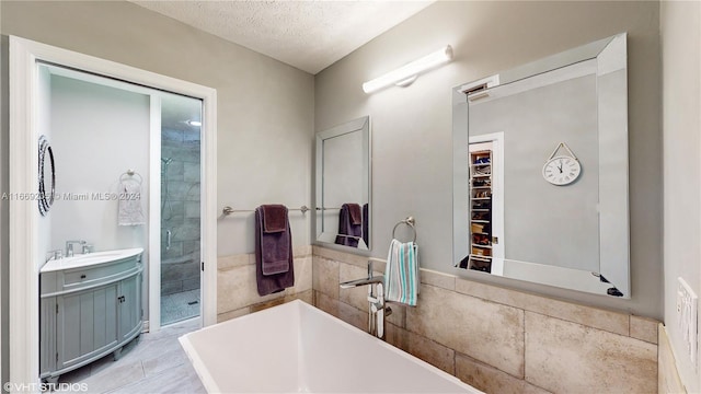 bathroom with vanity, a textured ceiling, and separate shower and tub